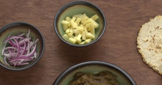 Sarson ka saag traditional Indian dish with corn bread (Makki di roti) with shallots and garlic. Homemade food meal. Table camera slide.