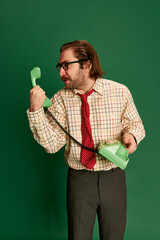 Portrait of retro mature man with moustache and beard in eyeglasses in vintage fashion clothes talking on phone over dark green background.