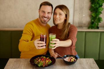Mid adult couple enjoy eating salads and drinking smoothies in salad bar