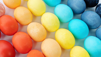 Easter rainbow colored eggs background. Colored eggs are laid out in a gradient and diagonally on a white background. Happy easter eggs in minimal style close up photo with copy space for a banner.