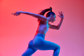 Speed. Dynamic image of young active girl, athlete, runner in motion, training over pink studio...