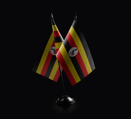 Small national flags of the Uganda on a black background