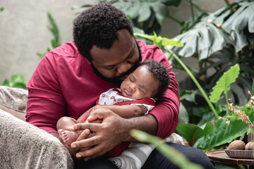 Father holding african american newborn baby while sleeping.