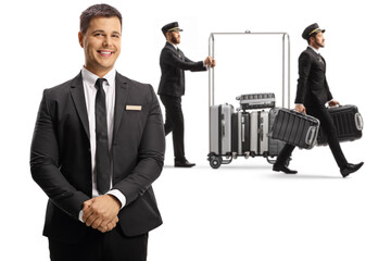 Hotel manager and bellboys carrying suitcases and pushing a luggage cart