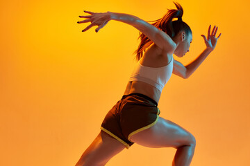 Speed, strength. Young girl, professional athlete, runner in motion, training over orange studio...