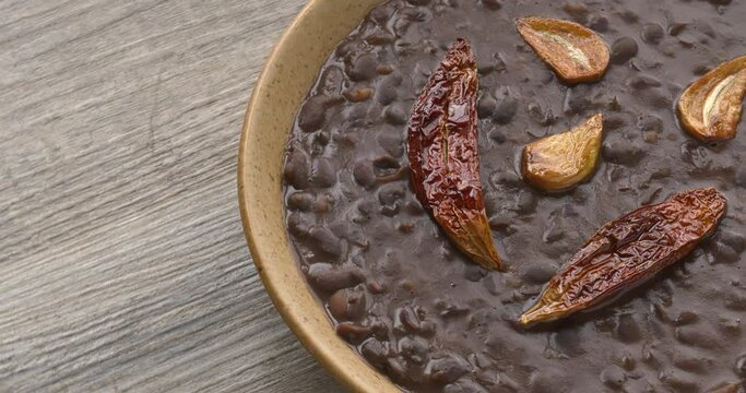Frijoles refritos with roasted garlic and dried roasted chili on top. Table spin. Seamless loop.