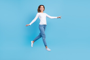 Fototapeta na wymiar Full length photo of adorable charming lady dressed white shirt walking jumping high emtpy space isolated blue color background