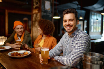 Happy smiling man sitting at sports bar counter desk looking at camera