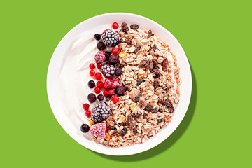 Muesli bowl or granola bowl with yogurt and berries on color background. Healthy breakfast, top view.