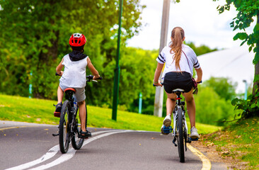 Fototapeta premium A boy and a girl ride bicycles in a city park 