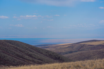 Unusual mountain landscape with bright cloudy skies. Autumn in remote foothills in northern China. Dry grassy and hills. Natural background. Exploration of new places, travel to remote locations.