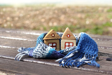 two models of separate wooden houses in a knitted scarf. warm and economical