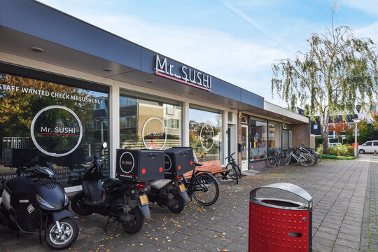 Amsterdam, Netherlands - 10 April, 2021: some motorcycles parked in front of a storefront with the words msh written on it and an orange trash can next to them