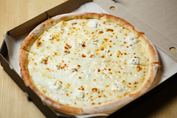 Four cheese pizza delivered in a box. Delicious Italian quattro formaggi dish baked in oven with...