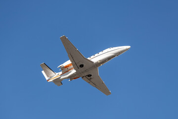 Scenic close bottom view modern luxury expensive white private jet plane dispatching from airport isolated on blue clear sky background. Executive aicraft vip travel concept. Service and maintenance