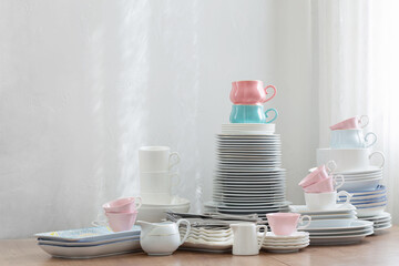 pink, white abd blue  cutlery on a wooden table against a white wall