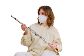 Woman musician with flute in medical face mask playing at home on sofa in living room, isolated on a white background