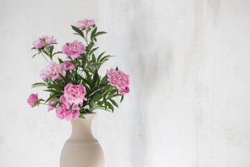 pink peony in ceramic vase on background old wall