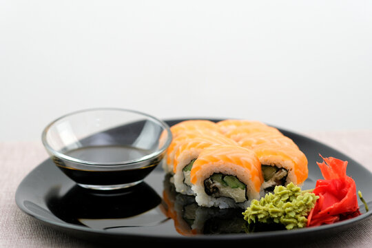 Salmon sushi set on a white plate. Sushi roll with red fish, salmon, red caviar. Roll with fresh salmon, soft avocado, with shrimp and crab and cream cheese under a wide layer of massago caviar