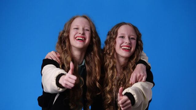 4k video of two twin girls are excited about something over pink background.