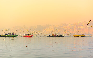 Tourists feeding the migratory birds at the popular boat tour on the sacred Ganges river in...