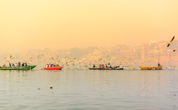 Tourists feeding the migratory birds at the popular boat tour on the sacred Ganges river in Varanasi, Uttar Pradesh, India
