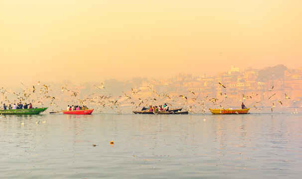 Tourists feeding the migratory birds at the popular boat tour on the sacred Ganges river in Varanasi, Uttar Pradesh, India