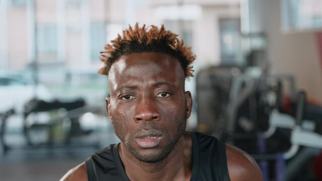 black man is training in fitness center, run on treadmill, closeup portrait of face, exhausted man