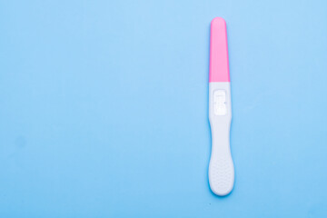 Unused pink and white pregnancy test on the blue background with copy space