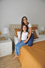 mãe e filha felizes juntas se divertindo em quarto decorado com tons dourados e brancos estilo...