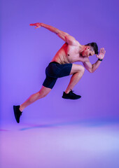 Fototapeta premium Athletic man with fit muscular body training in studio - Active man doing a workout, colorful lighting and background, concepts about fitness, sport and healthy lifestyle
