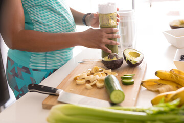 Midsection of mid adult african american woman preparing healthy breakfast in kitchen at home