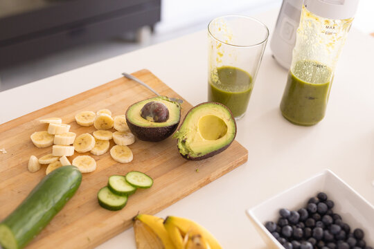 Fresh avocados and banana slices with healthy juice on kitchen island at home