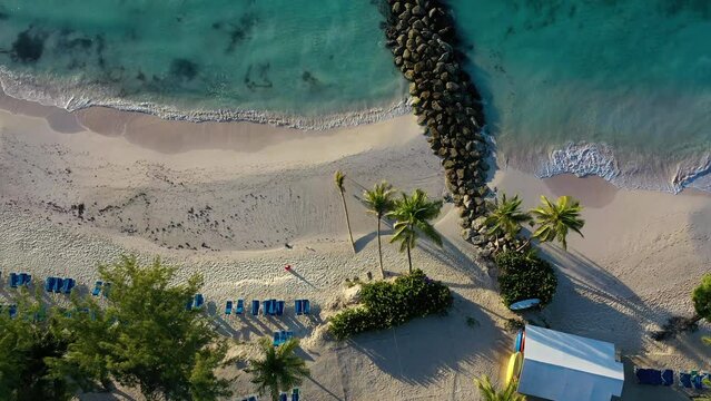 Drone view of shaded lounge chairs of resort to virgin beaches
