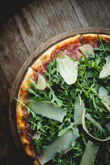 Appetizing pizza with meat, herbs and cheese on a dark wooden background