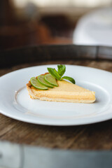 Lemon tart garnished with mint and lemon on a large white plate