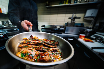 man chef cooking fried meat slice in frying pan on restaurant kitchen