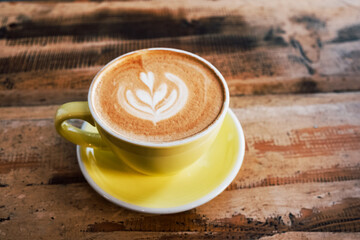 Freshly made delicious cappuccino coffee with beautiful latte art on shabby wooden background. Copy space for text. Morning hot drink.