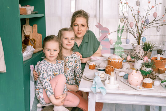 Easter. Happy Family Mom Together Little Kids Girls Have Fun Springtime Easter Holiday At Home Setting And Decorating Table Scape With Easter Cakes Bakery And Painted Eggs For Lunch Or Dinner