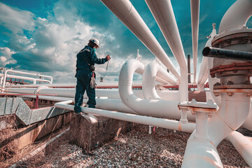 Male worker inspection at steel long pipes and pipe elbow in station oil factory during refinery...