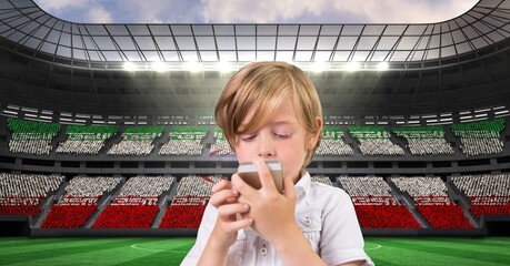 Composite image of caucasian boy using smartphone against sports stadium
