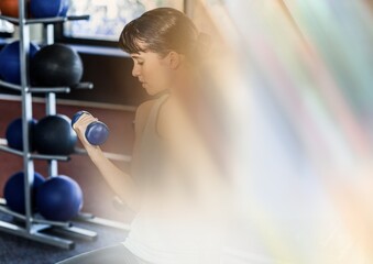 Blur effect overlay against caucasian fit woman working out with dumbbells at the gym