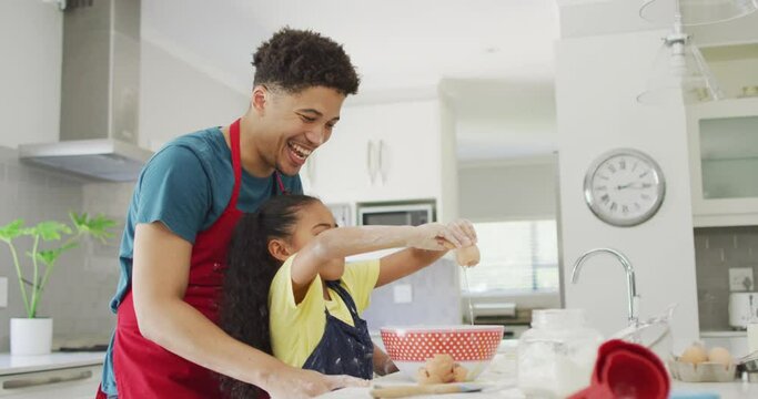 Happy biracial father and daughter baking together in kitchen