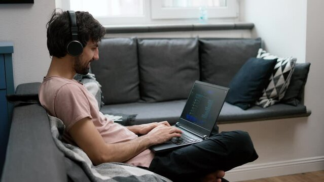 Caucasian man in headphones typing on laptop at home, social media comminication
