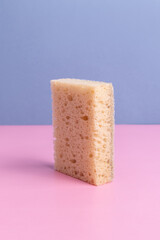 Sponge for washing dishes made of sisal. Sponge on blue and pink background. Vertical