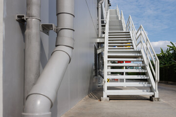 Obraz premium white fire exit stair of large building against blue sky. outdoor metal stair step. fire escape stair way.