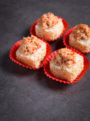Side view of sushi roll pieces in paper pack. Four Sushi pieces with salmon on dark concrete background.