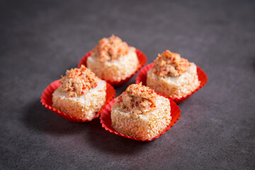 Side view of sushi roll pieces in paper pack. Four Sushi pieces with salmon on dark concrete background.