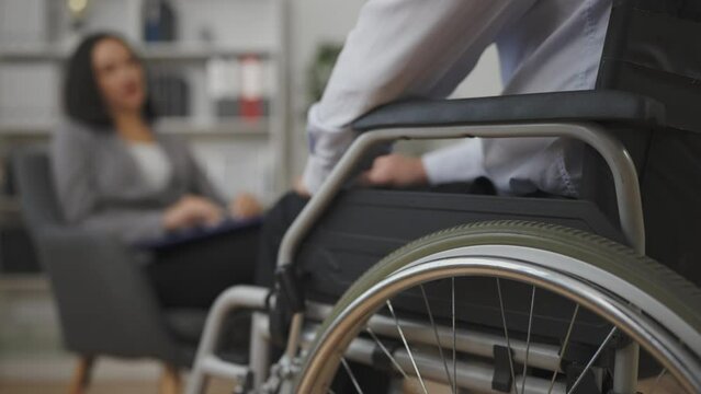 Female counselor talking with man wheelchair user, listening to patient, support