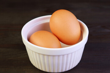 Closeup of Chicken Eggs in a White Bowl Isolated on Black Wooden Table